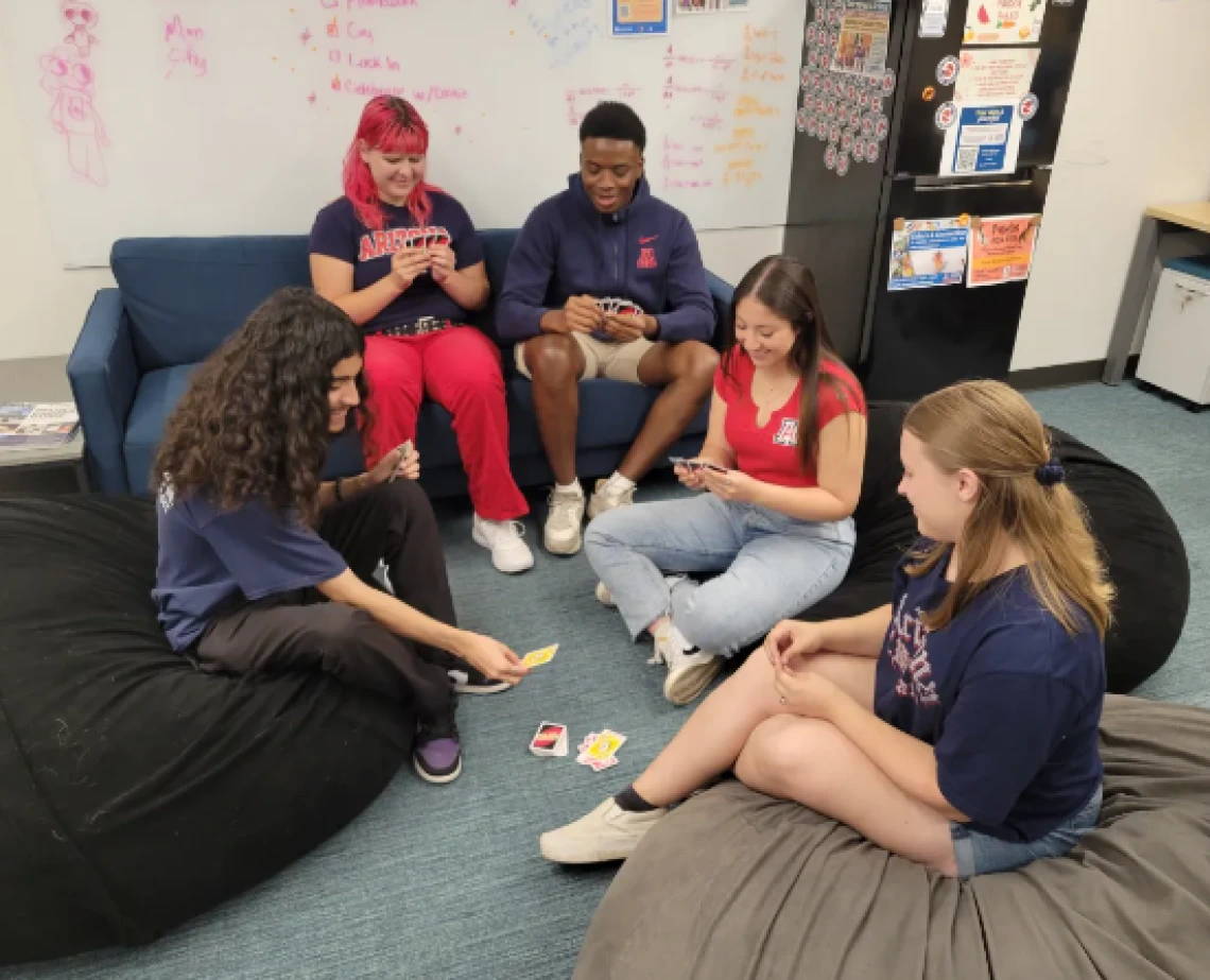 Group of students sitting on couches and beanbags smiling and playing uno